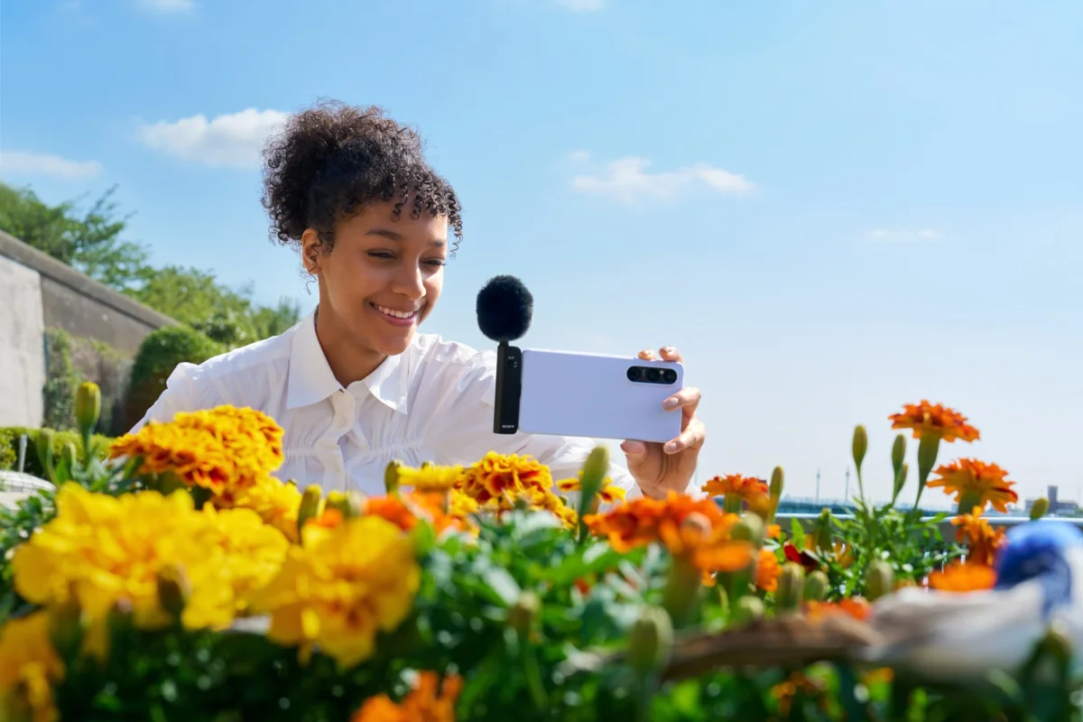 woman filming flowers with Sony spatial audio mic plugged into her phone